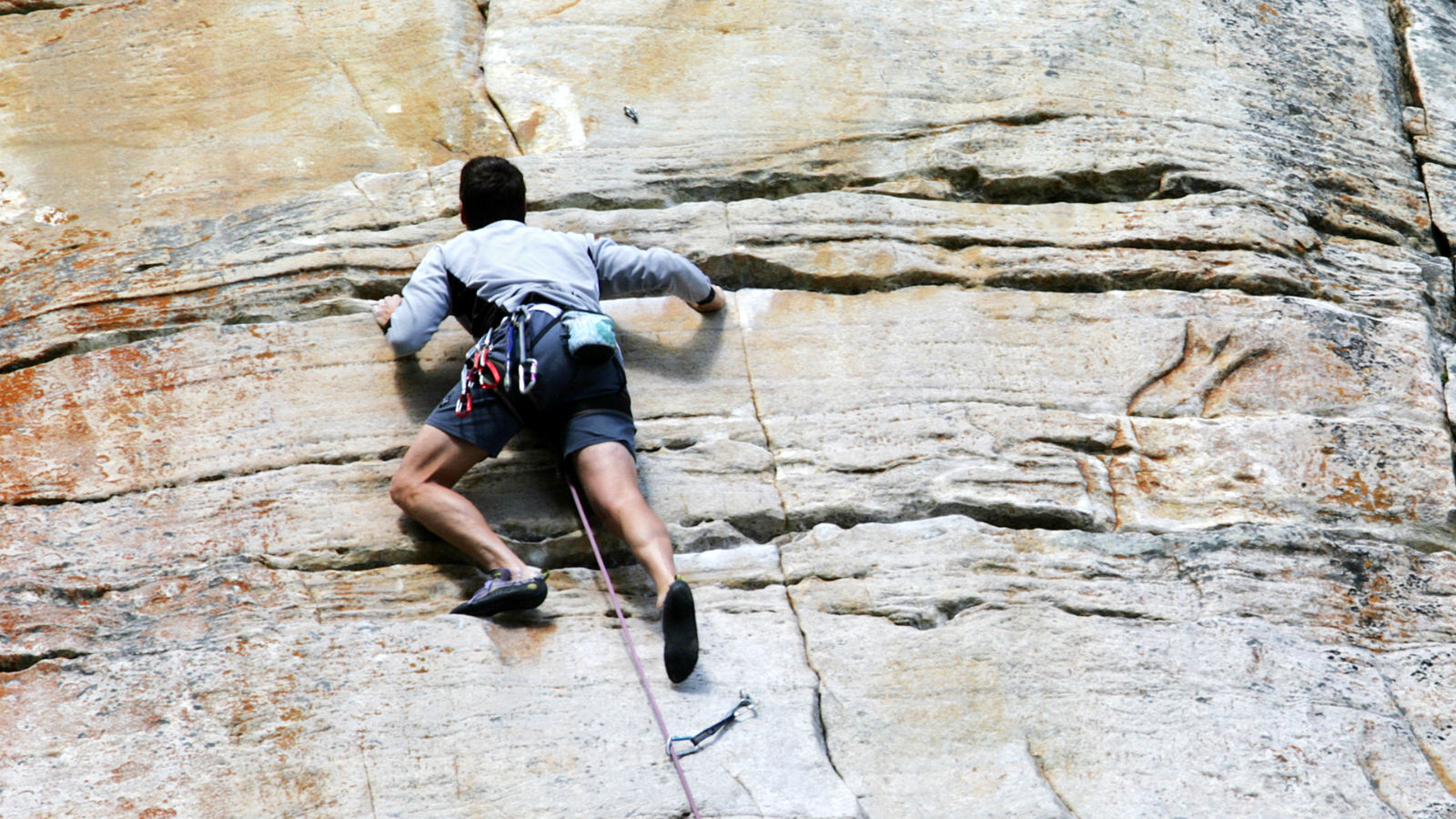 Professional scaling a rock face, symbolising the use of AI tools and resources to build organisational capability and confidence.